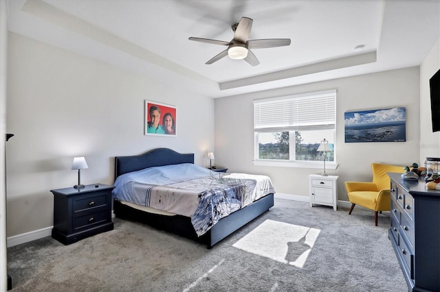 carpeted bedroom featuring ceiling fan and a tray ceiling