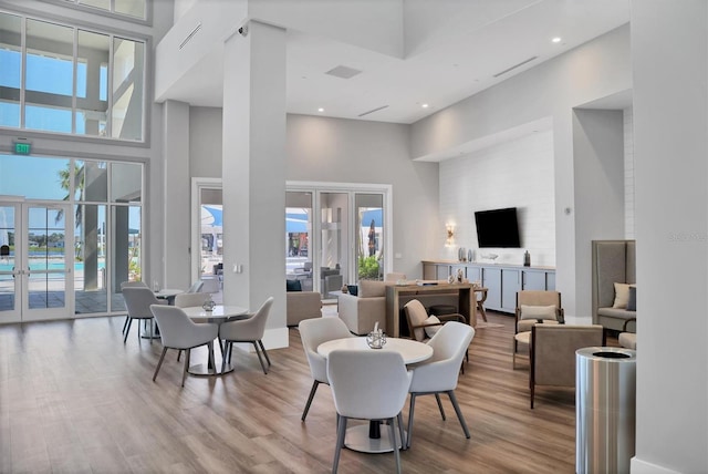 living room with light hardwood / wood-style floors, a towering ceiling, and french doors