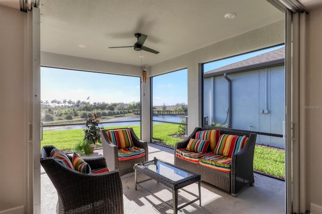 sunroom featuring ceiling fan and a water view