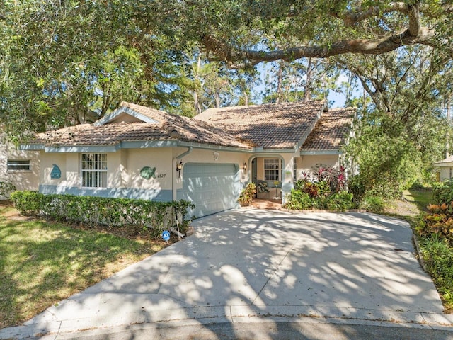 ranch-style house featuring a garage, concrete driveway, a tile roof, and stucco siding