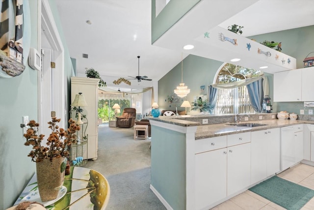 kitchen with white cabinets, light colored carpet, a peninsula, light stone countertops, and a sink