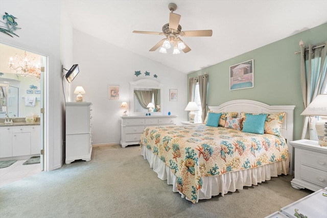 bedroom featuring a ceiling fan, light colored carpet, ensuite bath, vaulted ceiling, and a sink