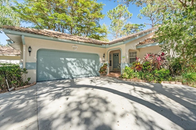 mediterranean / spanish house with concrete driveway, an attached garage, a tile roof, and stucco siding