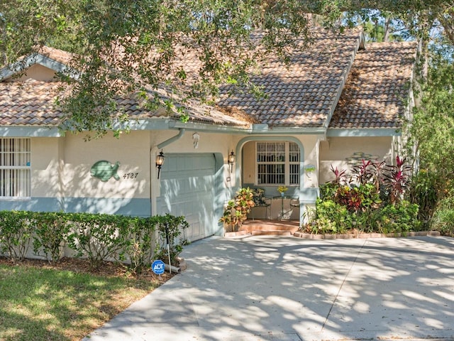 view of front of home with a garage, a tile roof, concrete driveway, and stucco siding