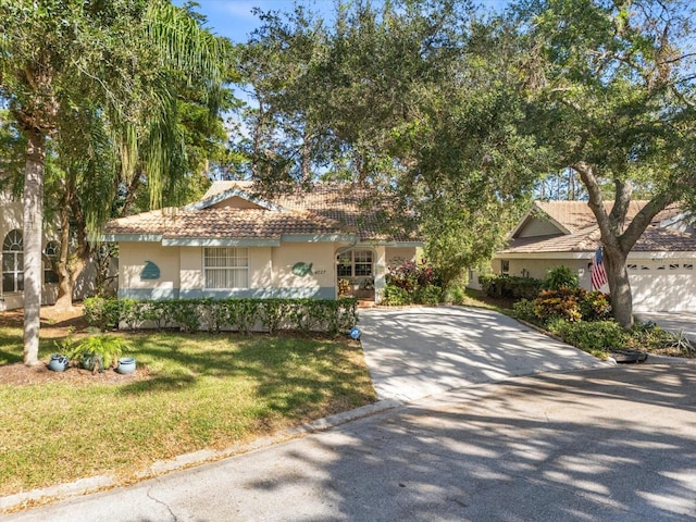 view of front of property featuring a tile roof, a front lawn, concrete driveway, and stucco siding