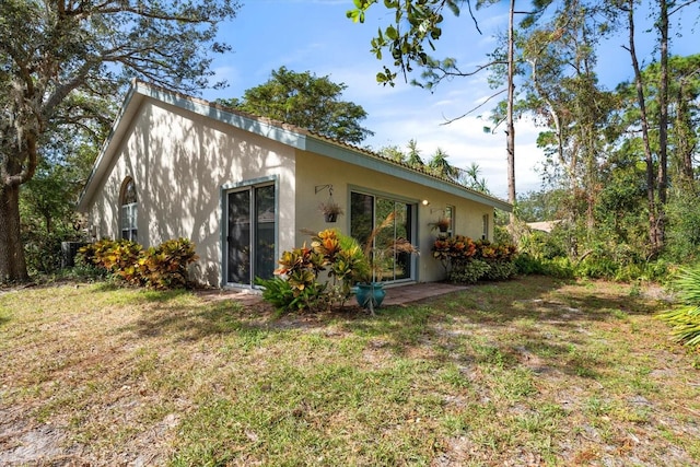 back of property featuring a yard and stucco siding