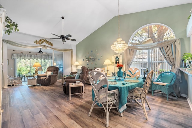 dining room featuring high vaulted ceiling, wood finished floors, and ceiling fan with notable chandelier