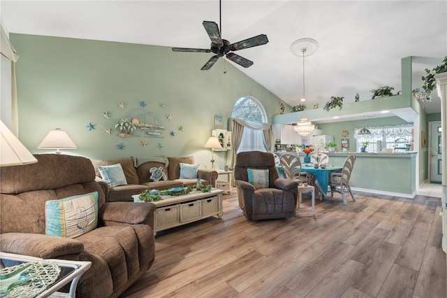 living room featuring ceiling fan, vaulted ceiling, baseboards, and wood finished floors