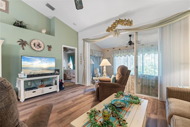 living room with lofted ceiling, visible vents, a ceiling fan, and wood finished floors