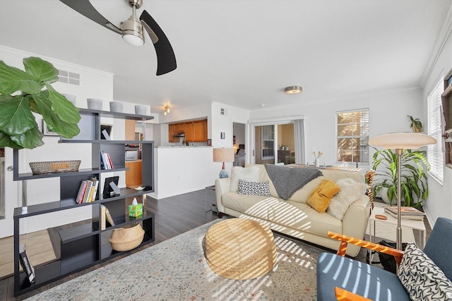 living room featuring dark hardwood / wood-style flooring, ceiling fan, and crown molding