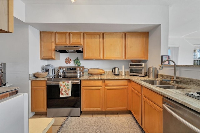 kitchen featuring light tile patterned flooring, appliances with stainless steel finishes, light stone counters, and sink