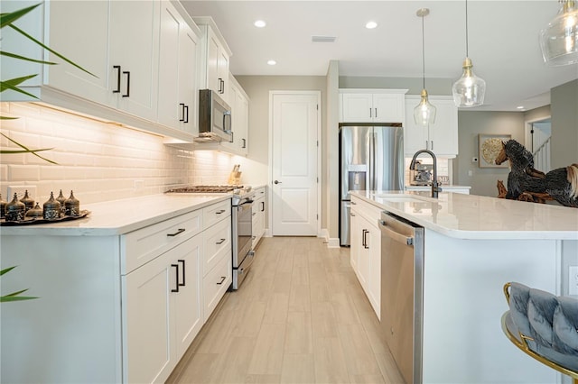 kitchen with pendant lighting, white cabinets, stainless steel appliances, and sink