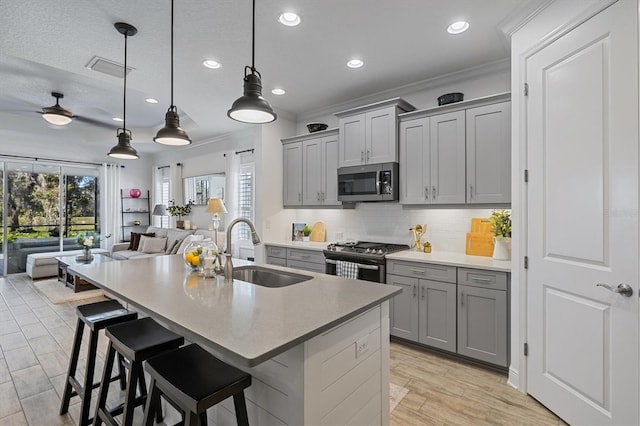 kitchen with a breakfast bar, sink, hanging light fixtures, and appliances with stainless steel finishes