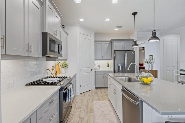 kitchen featuring sink, light hardwood / wood-style floors, decorative light fixtures, appliances with stainless steel finishes, and ornamental molding