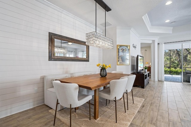 dining room featuring wooden walls, a textured ceiling, hardwood / wood-style flooring, and ornamental molding