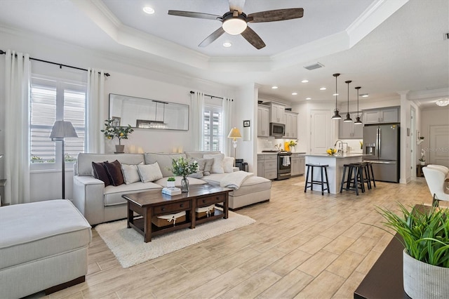 living room featuring a raised ceiling, crown molding, plenty of natural light, and ceiling fan