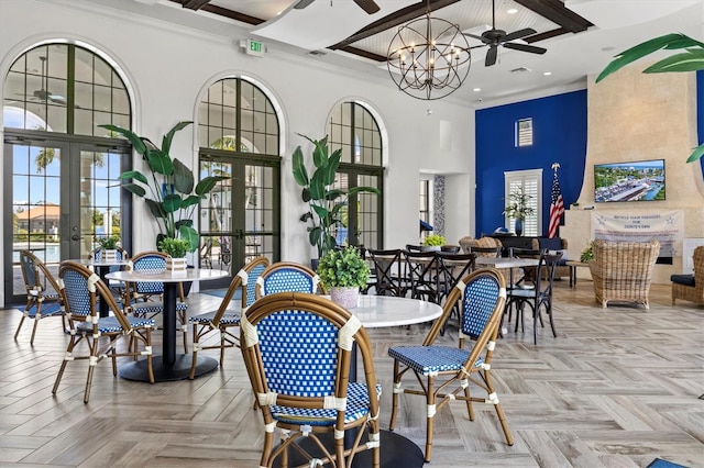 dining room with french doors, crown molding, a towering ceiling, light parquet flooring, and ceiling fan with notable chandelier