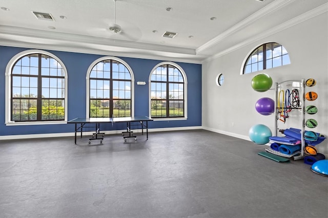 exercise room featuring ceiling fan, ornamental molding, a textured ceiling, and a tray ceiling