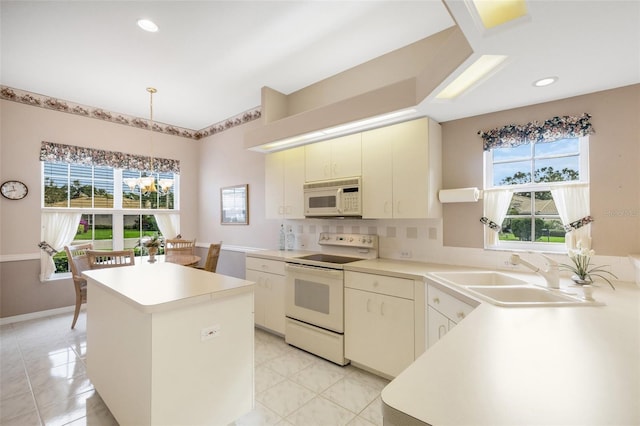 kitchen with a center island, white appliances, backsplash, sink, and decorative light fixtures