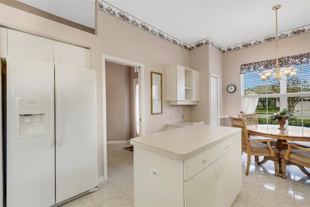 kitchen with white cabinets, white refrigerator with ice dispenser, hanging light fixtures, and an inviting chandelier