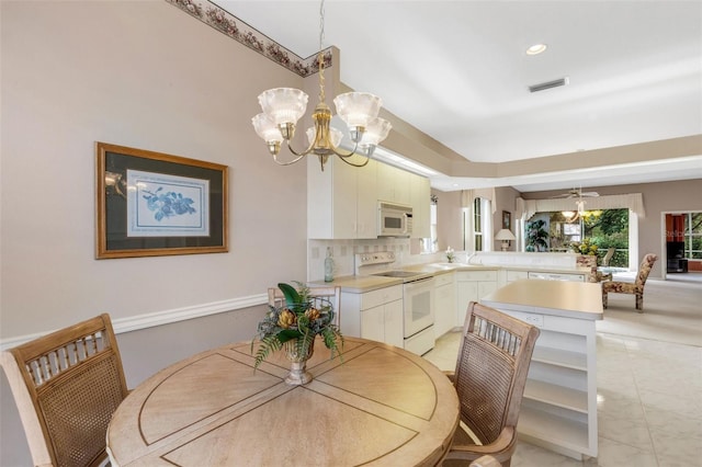 tiled dining space featuring ceiling fan with notable chandelier