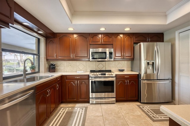 kitchen featuring a tray ceiling, sink, light tile patterned flooring, and appliances with stainless steel finishes