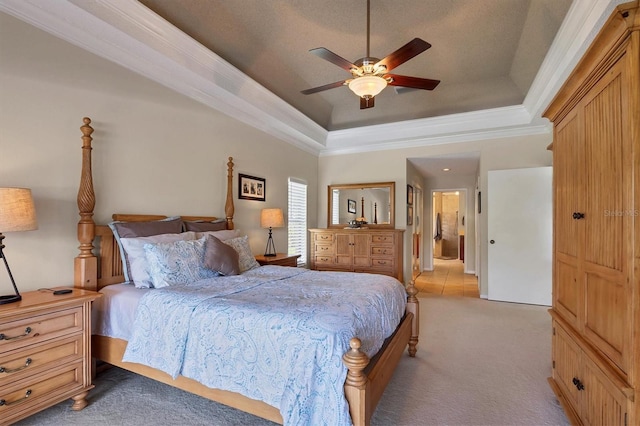 bedroom with ceiling fan, light colored carpet, ornamental molding, and a tray ceiling