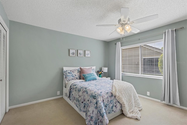 bedroom with a textured ceiling, ceiling fan, light carpet, and a closet