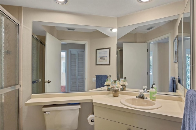 bathroom featuring vanity, an enclosed shower, and toilet