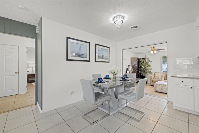 tiled dining room with ceiling fan and a textured ceiling