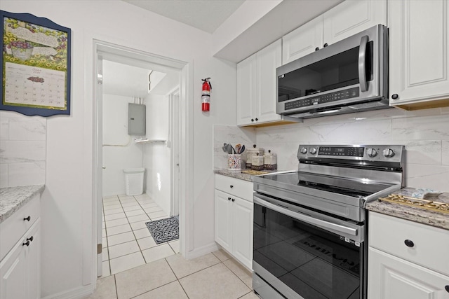 kitchen featuring tasteful backsplash, white cabinetry, light tile patterned floors, and stainless steel appliances