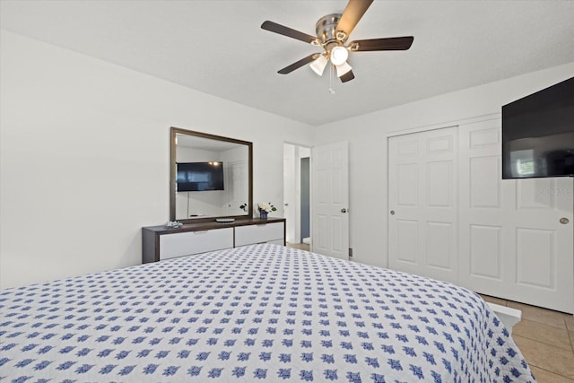 tiled bedroom featuring ceiling fan, a textured ceiling, and a closet