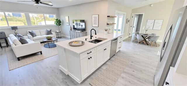 kitchen featuring a sink, open floor plan, white cabinetry, appliances with stainless steel finishes, and light countertops