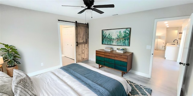 bedroom featuring visible vents, ceiling fan, baseboards, and a barn door