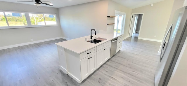 kitchen featuring light wood finished floors, a sink, light countertops, white cabinets, and appliances with stainless steel finishes