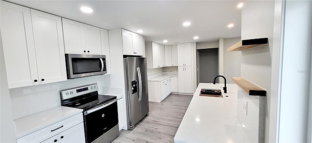 kitchen with a sink, recessed lighting, light wood-type flooring, and stainless steel appliances