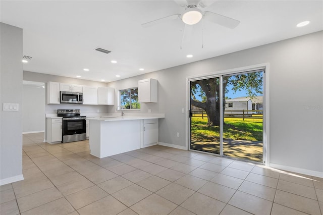 kitchen with ceiling fan, stainless steel appliances, light tile patterned floors, kitchen peninsula, and white cabinets