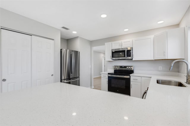 kitchen with light stone countertops, sink, white cabinets, and stainless steel appliances