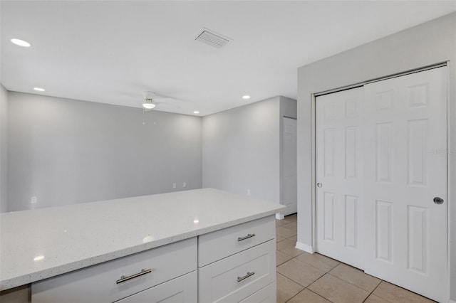 kitchen with white cabinetry, light stone countertops, ceiling fan, and light tile patterned floors