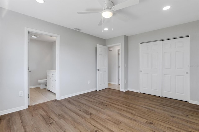 unfurnished bedroom with ceiling fan, light hardwood / wood-style floors, ensuite bath, and a closet