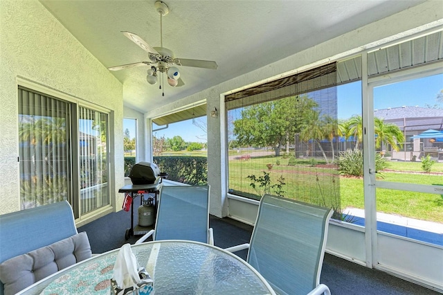 sunroom / solarium with vaulted ceiling, a wealth of natural light, and ceiling fan