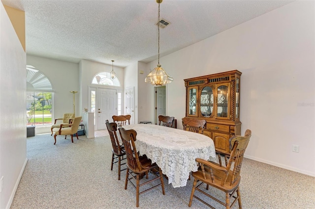 dining area with light colored carpet, a textured ceiling, and a notable chandelier