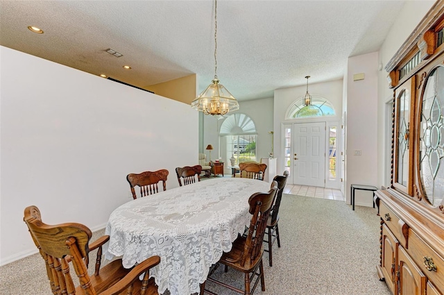 carpeted dining room featuring a textured ceiling and an inviting chandelier