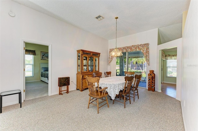 carpeted dining room with a textured ceiling and an inviting chandelier