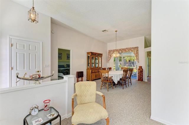 carpeted dining area featuring a textured ceiling and an inviting chandelier