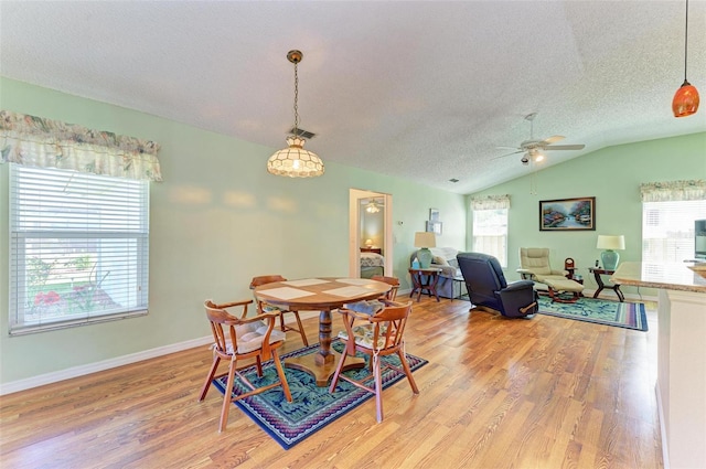 dining space with a textured ceiling, ceiling fan, light hardwood / wood-style flooring, and lofted ceiling