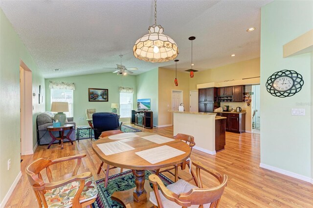 dining space featuring a textured ceiling, ceiling fan, light hardwood / wood-style flooring, and vaulted ceiling