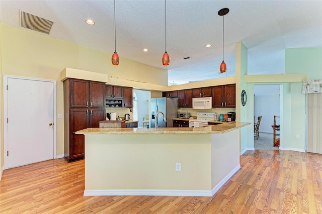 kitchen with white appliances, light hardwood / wood-style floors, and hanging light fixtures