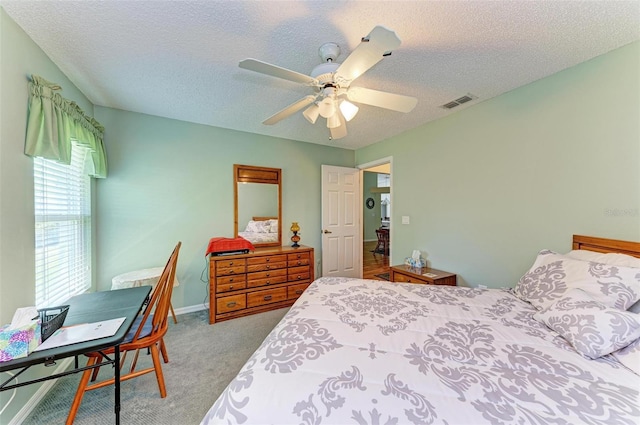 bedroom with a textured ceiling, light colored carpet, and ceiling fan