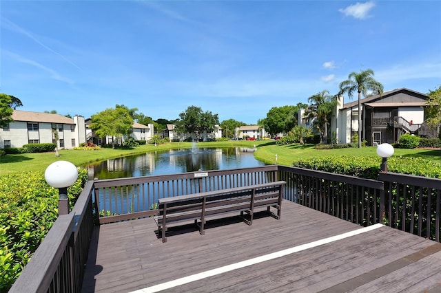 wooden terrace with a water view and a lawn